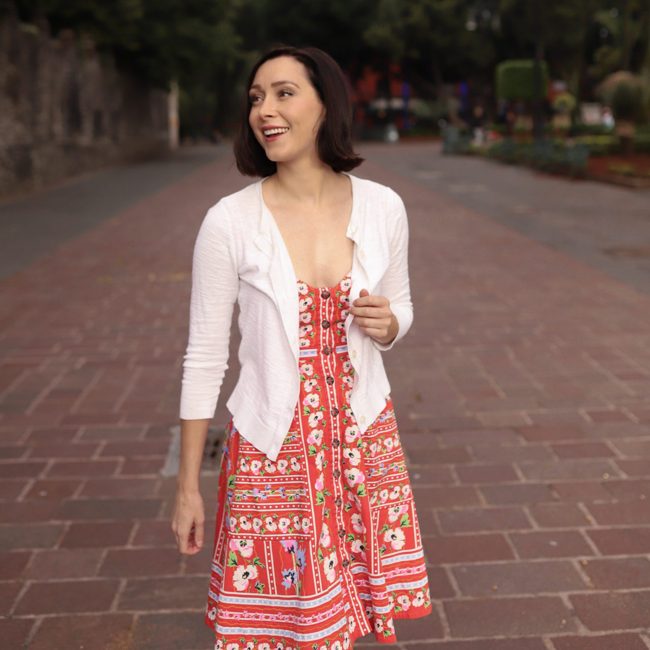 Travel Blogger Jordan Gassner smiling while walking down a long red brick path in Jardín Centenario in Coyoacán Mexico City