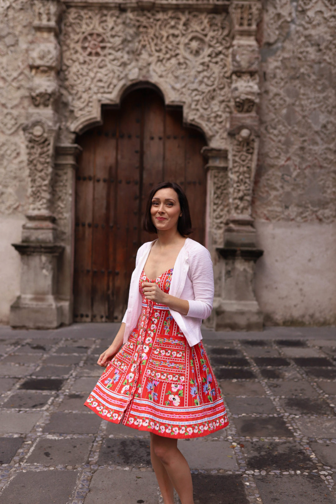 Travel Blogger Jordan Gassner twirling and smiling in a red dress in front of Capilla de La Conchita in Coyoacán Mexico City