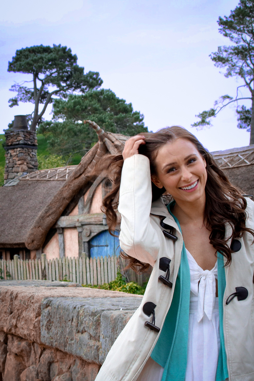 Travel Blogger Jordan Gassner smiling in front of the mill at Hobbiton Movie Set in Matamata, New Zealand