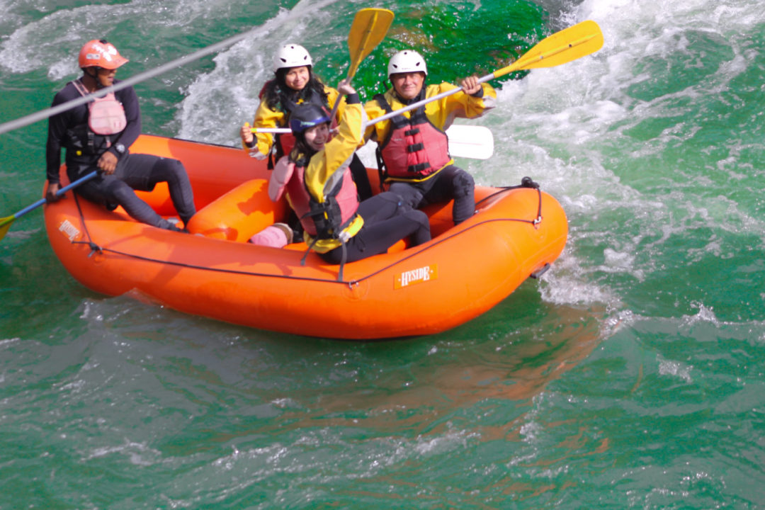 Travel Blogger Jordan Gassner and three other rafters celebrating after making it through a big rapid in Arequipa's RIo Chili River