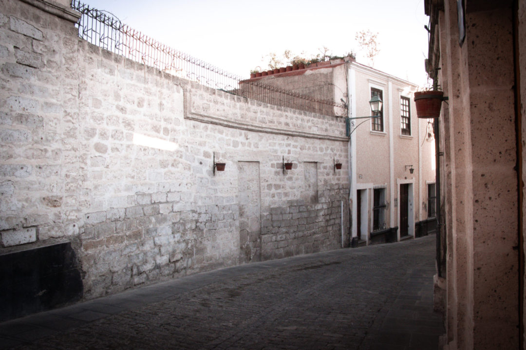 An old white sillar wall and white-pink houses along a street in Arequipa's Barrio de San Lázaro