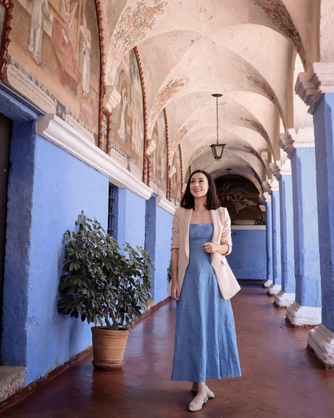Travel Blogger Jordan Gassner standing under a blue colonnade inside of the best sights in Arequipa: Santa Catalina Monastery