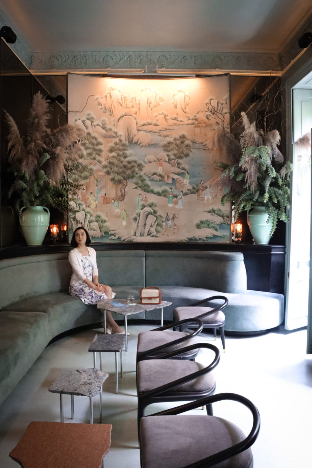 Travel Blogger Jordan Gassner sitting past a few tables inside the pink and mint interior at Bar Rosetta in Mexico City