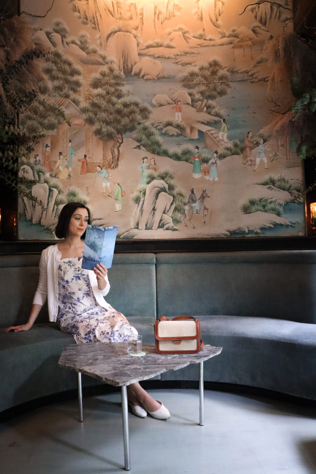 Travel Blogger Jordan Gassner reading a drinks menu inside the pink and mint interior at Bar Rosetta in Mexico City