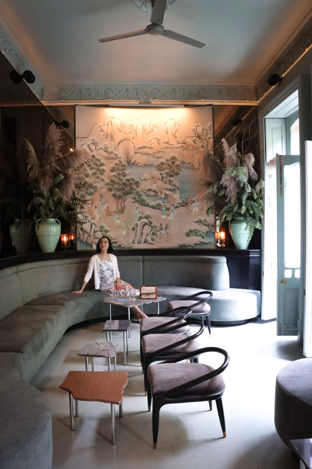 Travel Blogger Jordan Gassner sitting and looking at the pink and mint decor inside Bar Rosetta in Mexico City