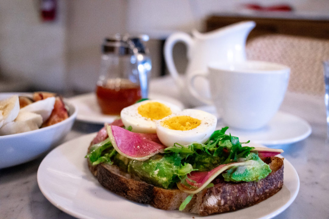 Avocado Toast with Soft Boiled Eggs, Tea and a fruit dish from Café Milou: a great restaurant for eating dairy-free in Mexico City