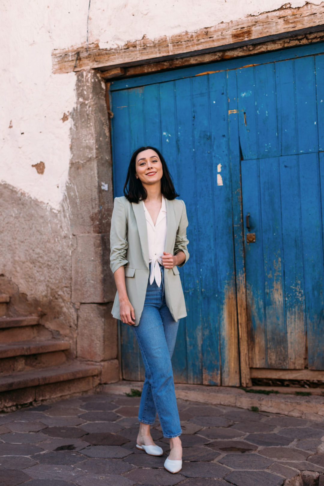 Travel Blogger Jordan Gassner standing and smiling near a blue door in the San Blas neighborhood in Cusco, Peru