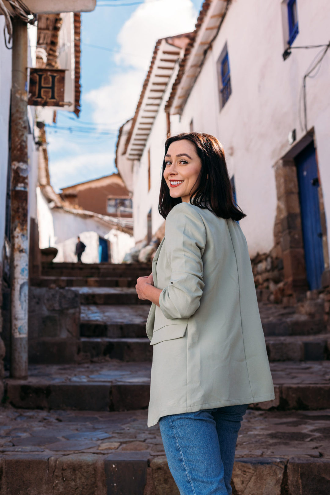 Travel Blogger Jordan Gassner walking up some steps and smiling over her shoulder in Cusco, Peru