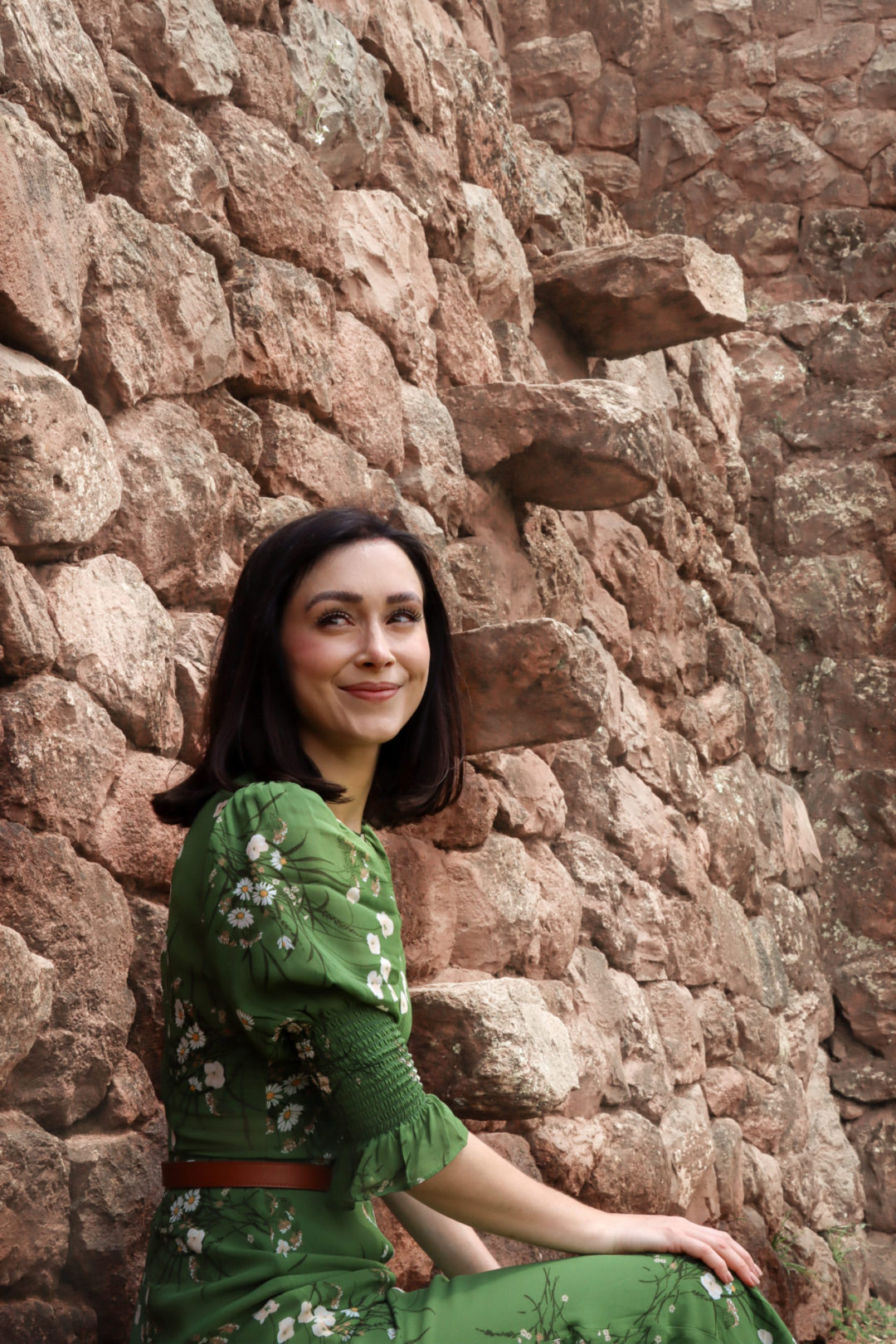 Travel Blogger Jordan Gassner sitting with her hand in the sun and on her knee at a ruin near Cusco
