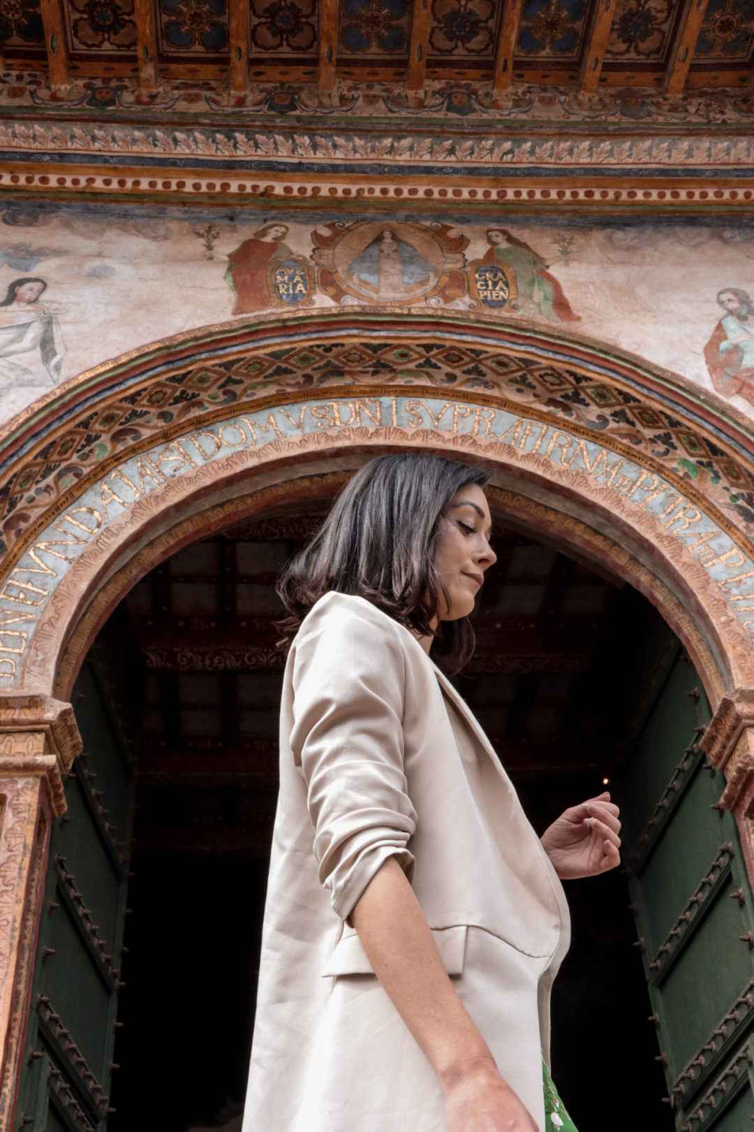 Travel Blogger Jordan Gassner looking down while standing beneath the intricately painted roof underneath the front of Andahuaylillas Church in Peru