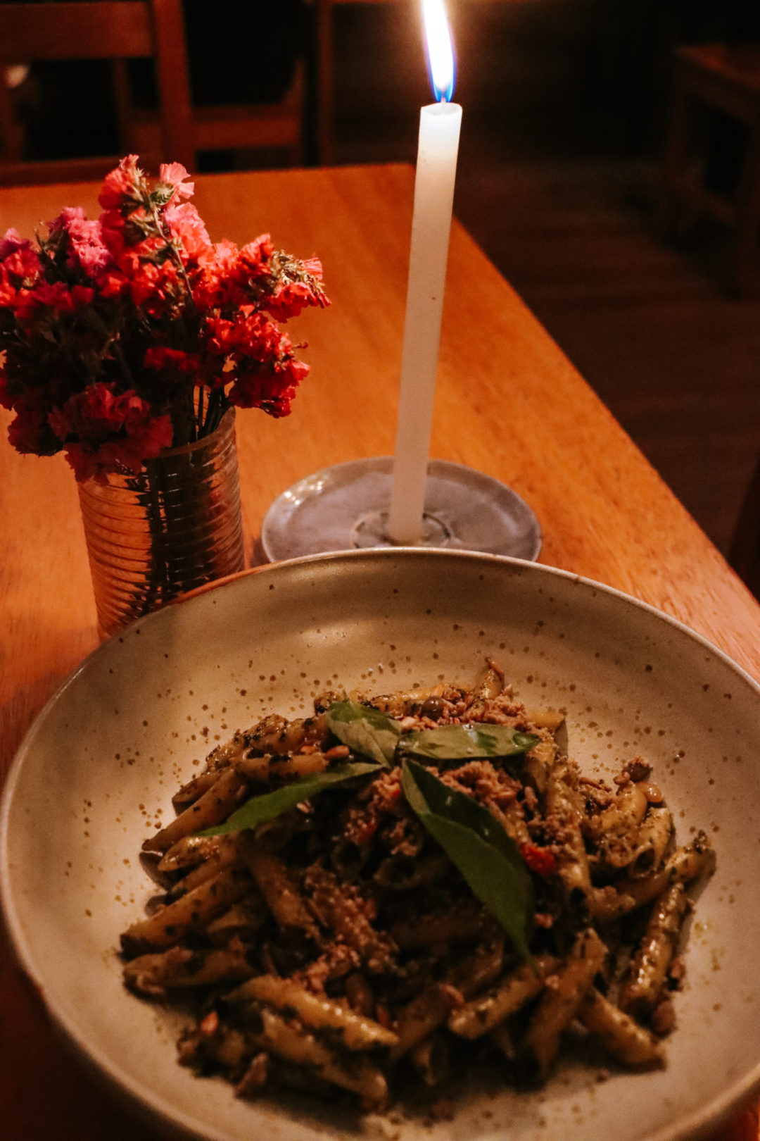 A bowl of pasta next to a candle and bouquet of flowers from Local Restaurante in Cusco, Peru