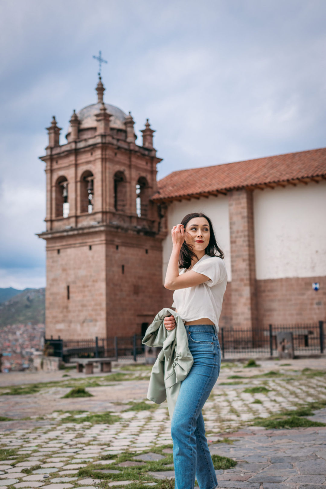 Travel Blogger Jordan Gassner brushing her hair from her face on top of Mirador de Plaza Sán Cristobal in Cusco, Peru
