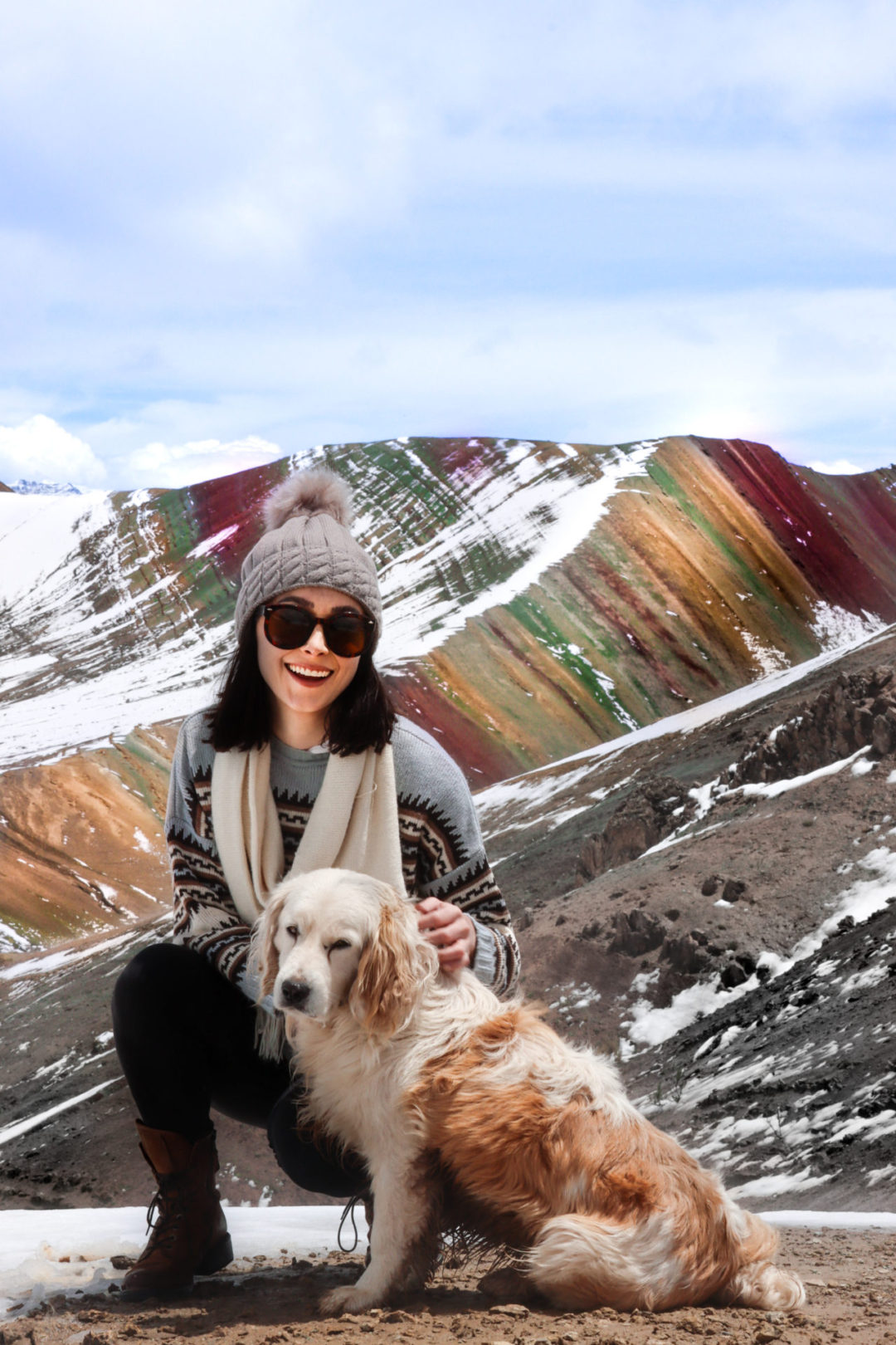 Jordan Gassner petting a guide's dog on top of Palccoyo Rainbow Mountain near Cusco, Peru