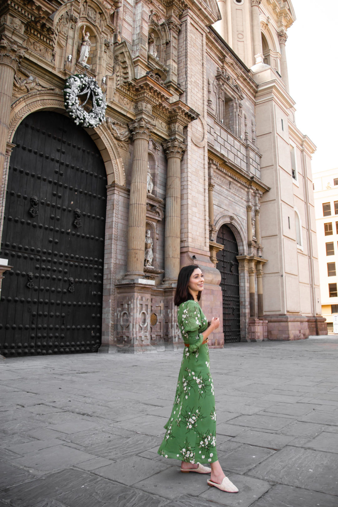 Travel Blogger Jordan Gassner wearing a green Reformation dress in front of Lima Cathedral in Peru