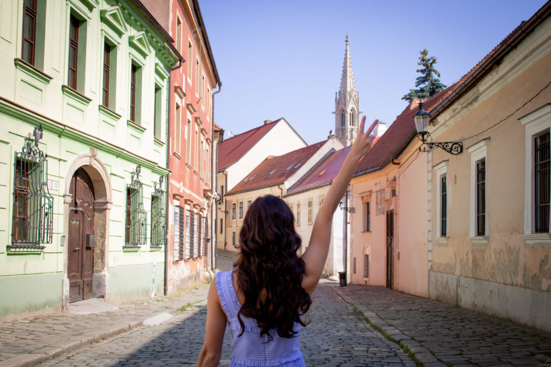 Travel BloggerJordan Gassner holding up a peace sign on the medieval Kapitulska Street in Old Town Bratislava