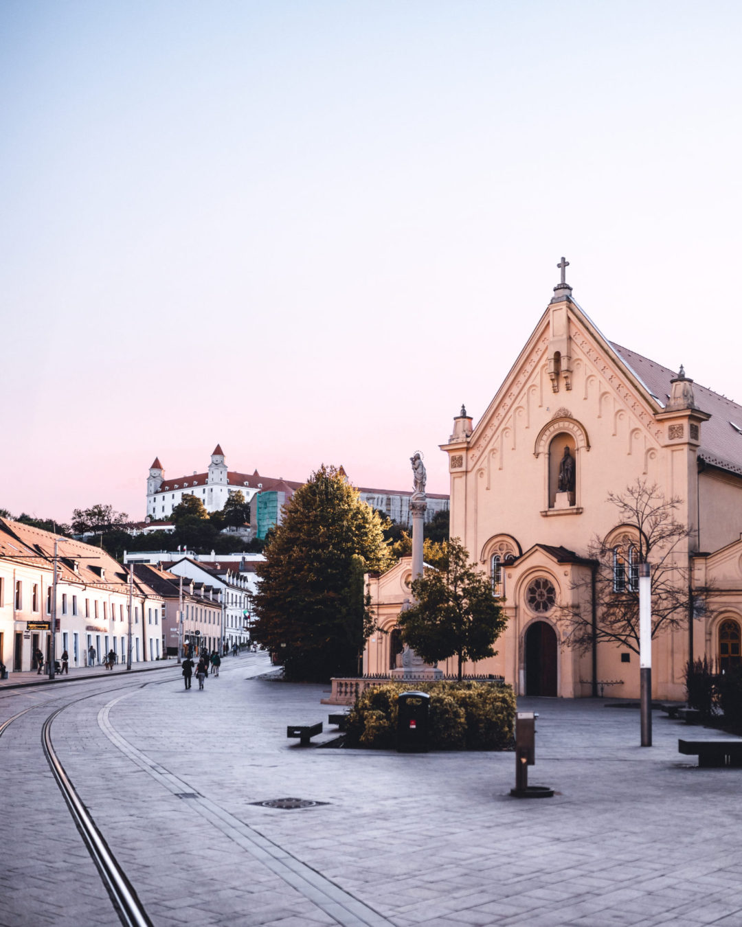 Bratislava Travel Guide: A tram rail through an empty street in Old Town, Bratislava Castle standing tall in the background