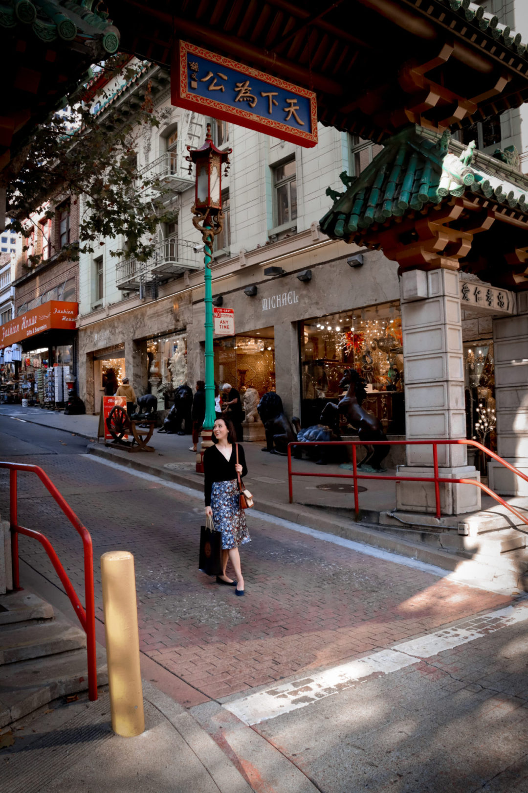 Travel Blogger Jordan Gassner smiling and holding a shopping bag while walking through the Dragon's Gat Archway of San Francisco's Chinatown