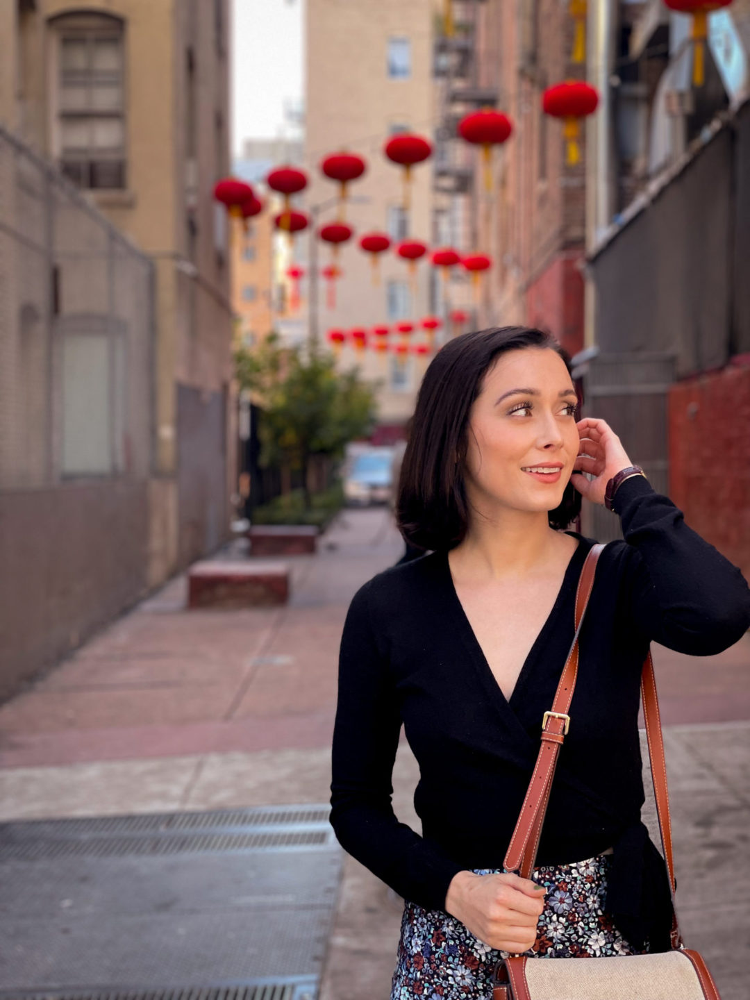 Travel Blogger Jordan Gassner about to speak while brushing her hair behind her ear in the lantern-strewn Hang Ah Street of San Francisco's Chinatown