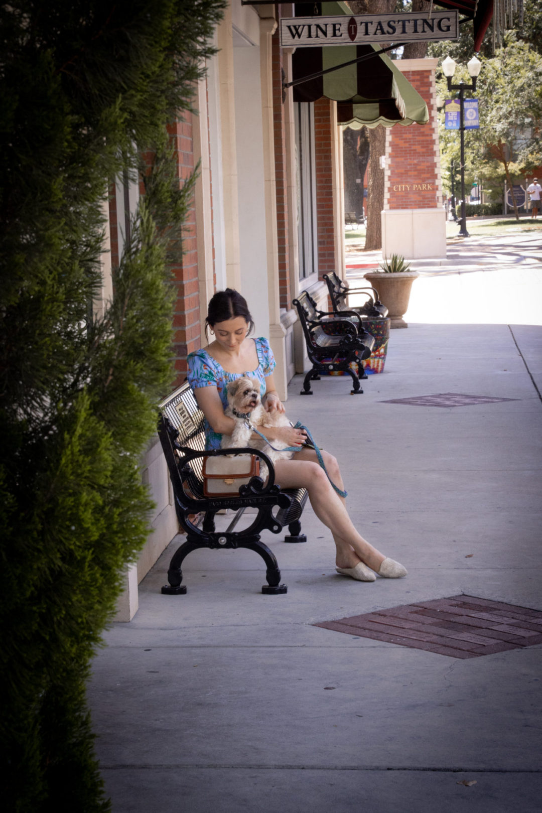 Travel Blogger Jordan Gassner sitting with her dog Charlie on a Bench in Downtown Paso Robles in Central California
