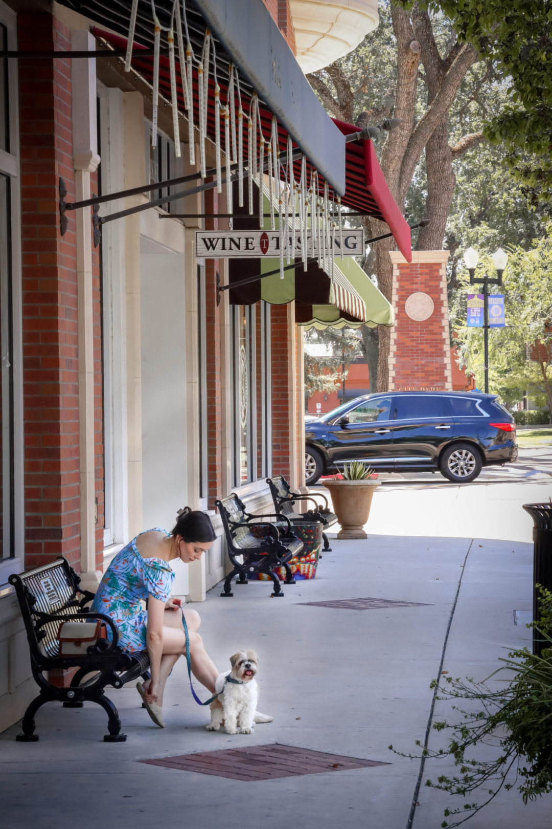 Travel Blogger Jordan Gassner fixing her shoe while sitting on a bench next to her dog, Charlie, in Paso Robles, California, USA