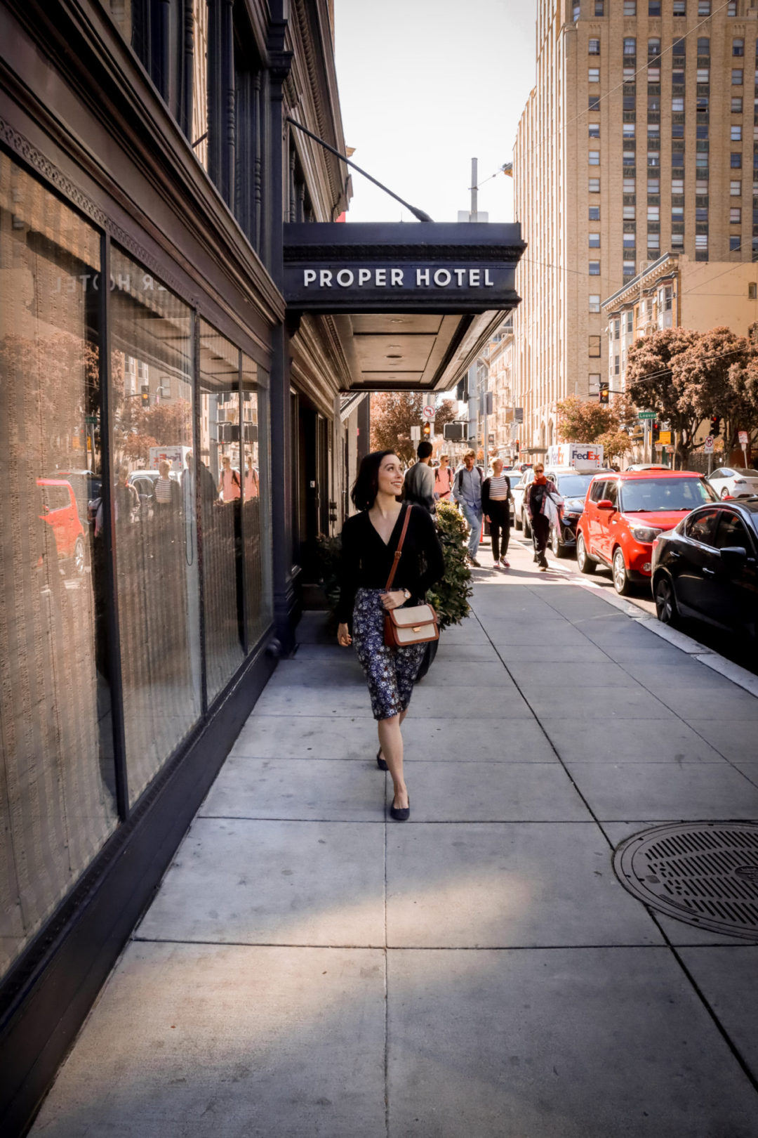 Travel Blogger Jordan Gassner smiling and walking in front of The San Francisco Proper Hotel awning