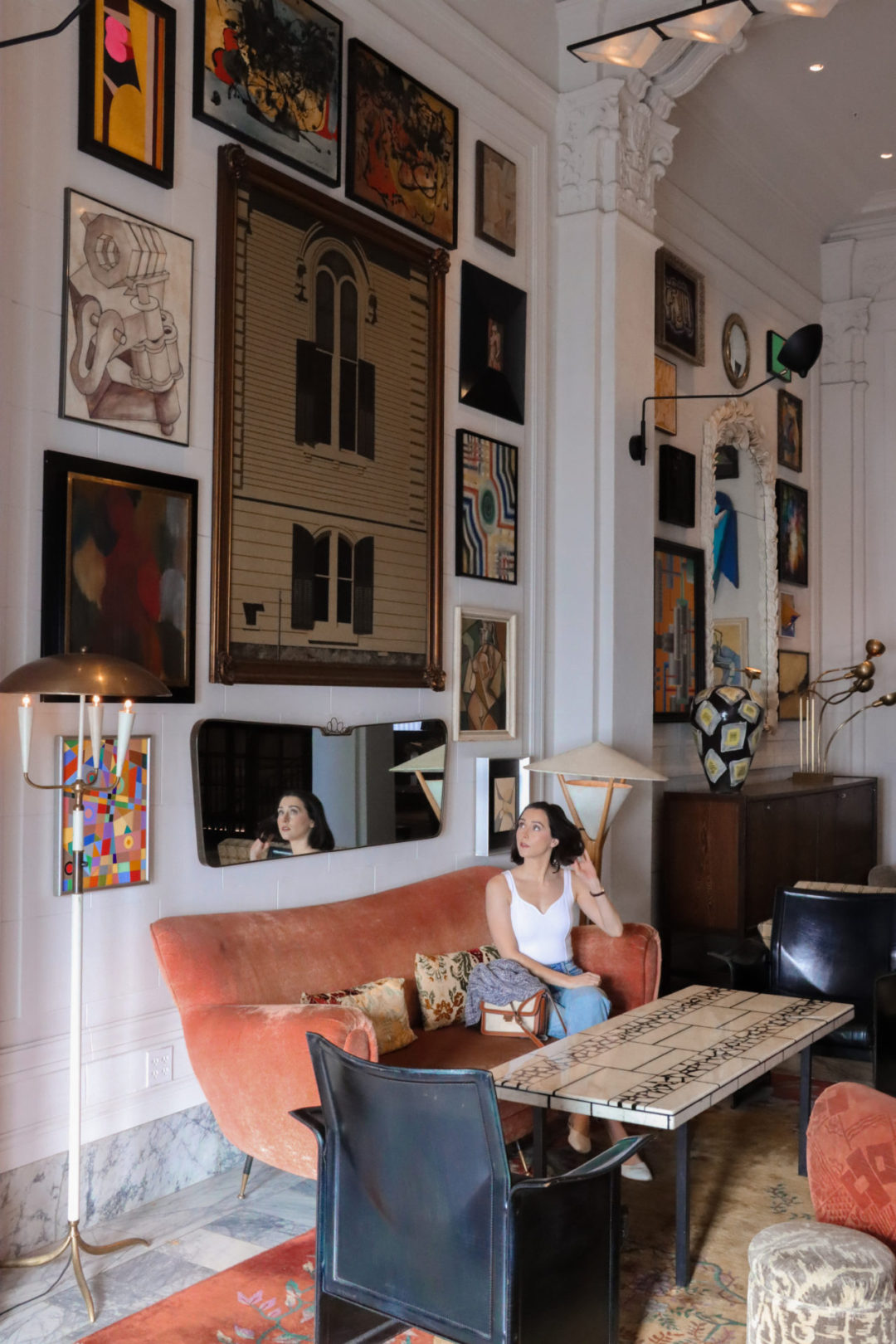 Travel Blogger Jordan Gassner on a coral sofa and playing with her hair in the Kelly Wearstler designed San Francisco Proper Hotel Lobby