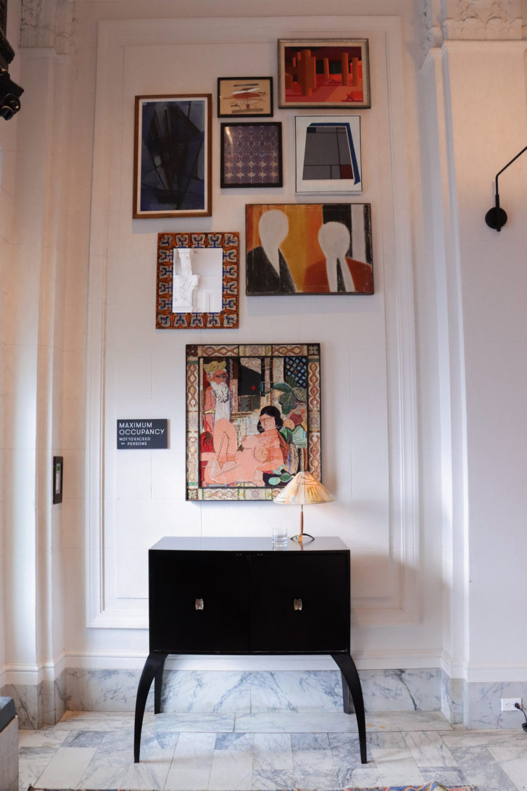 A gallery wall filled with bright, eclectic artwork in the Kelly Wearstler-designed San Francisco Proper Hotel lobby