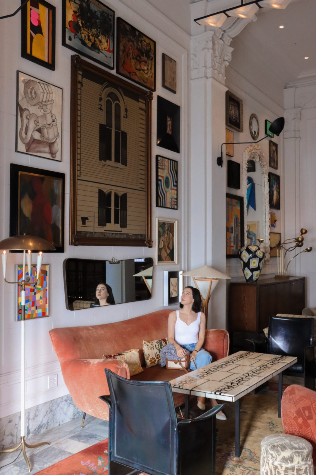 Travel Blogger Jordan Gassner on a coral sofa and looking at artwork in the Kelly Wearstler designed San Francisco Proper Hotel Lobby