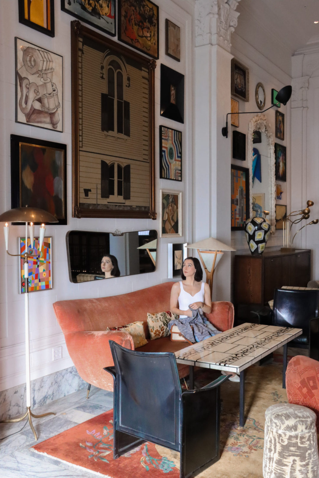 Travel Blogger Jordan Gassner on a coral sofa in the Kelly Wearstler designed San Francisco Proper Hotel Lobby