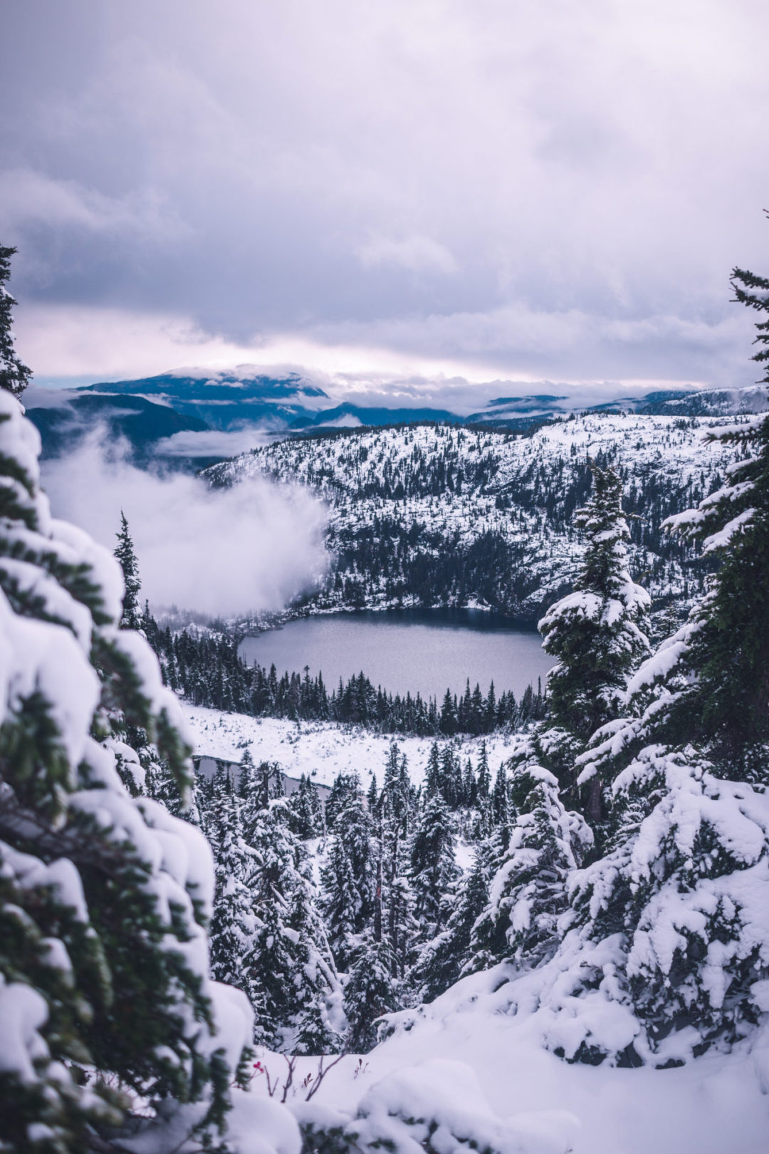 An alpine lake surrounded by a snowy, forest mountain landscape near Banff, Canada
