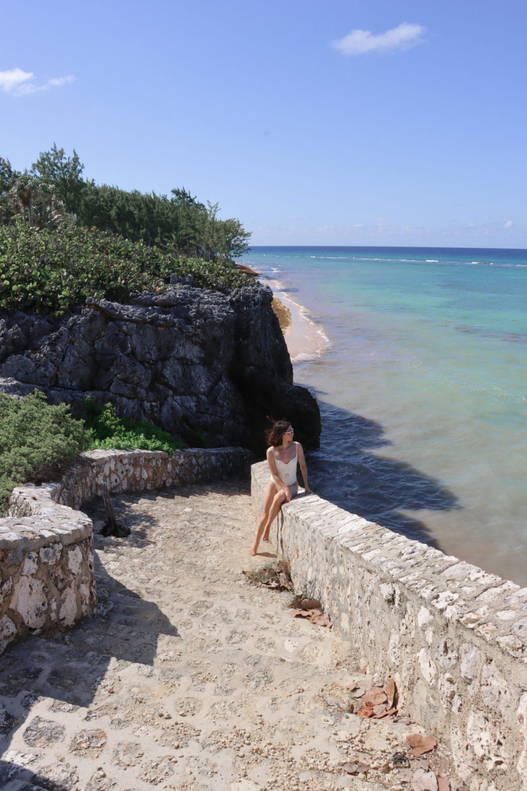 Travel Blogger Jordan Gassner peering out over the ocean from the Barefoot Beach stone ocean staircase on Grand Cayman in the Caribbean