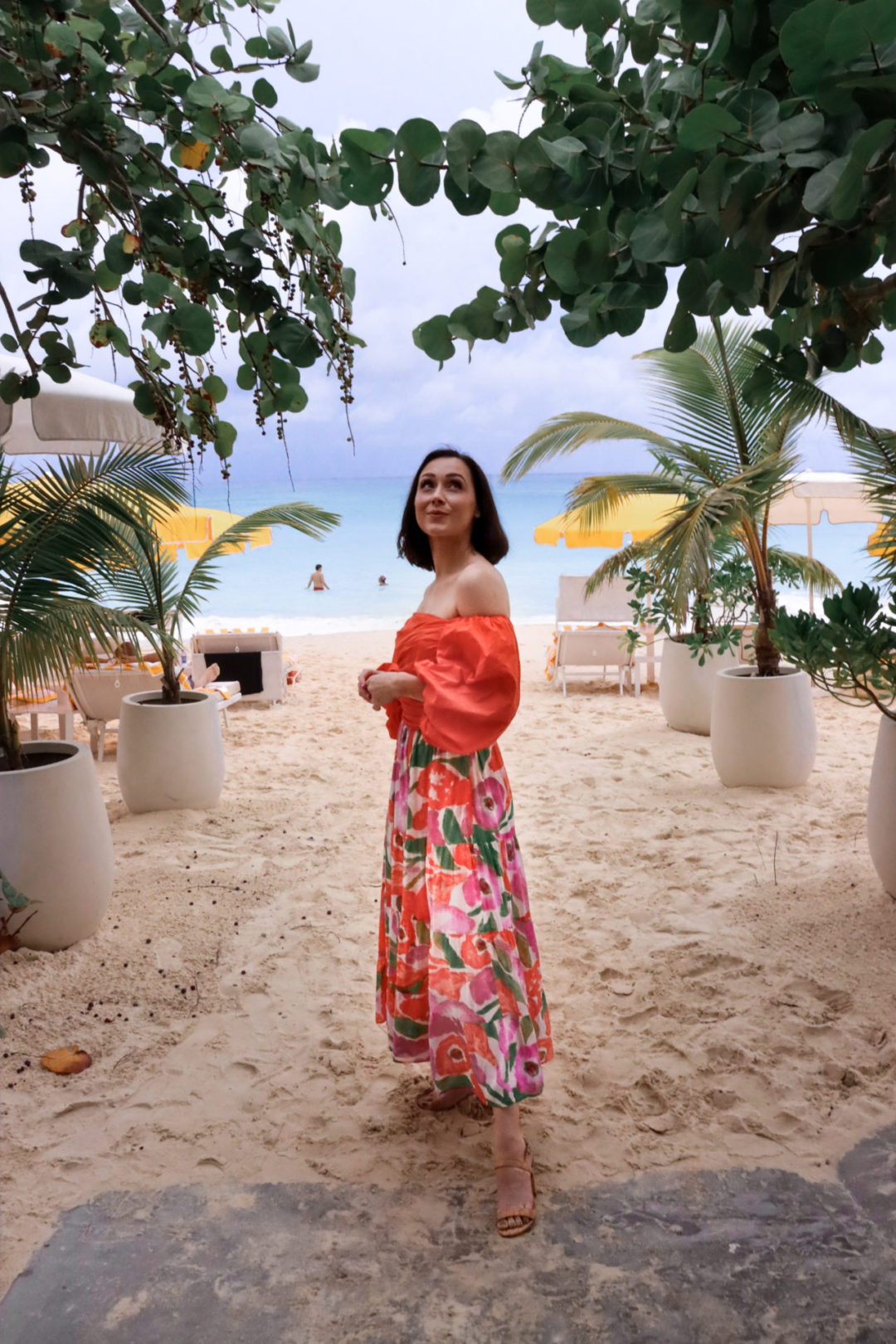 Travel Blogger Jordan Gassner standing under a green shaded hotel pathway leading to Seven Mile Beach on Grand Cayman Island