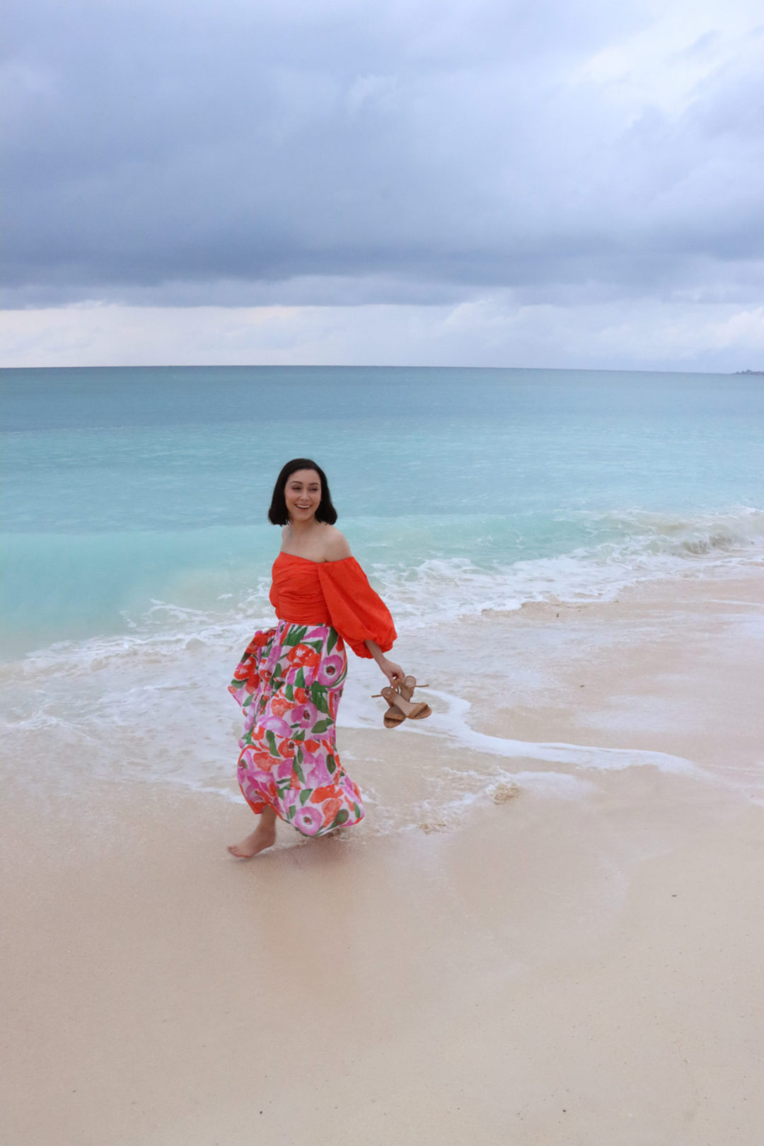 Travel Blogger Jordan Gassner smiling and walking alone the shore of Seven Mile Beach on Grand Cayman Island 