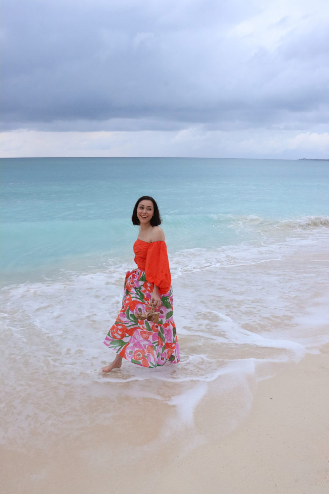Travel Blogger Jordan Gassner laughing and walking along the turquoise shoreline of Seven Mile Beach on Grand Cayman Island