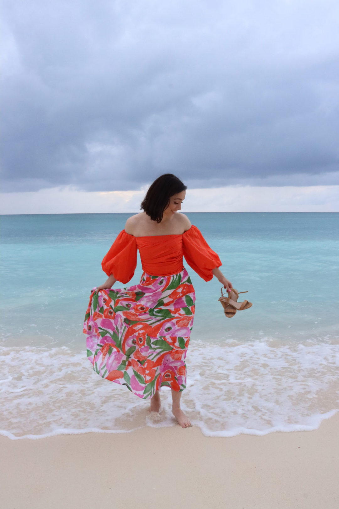 Travel Blogger Jordan Gassner smiling near the turquoise blue shoreline of Seven Mile Beach on Grand Cayman Island in the Caribbean