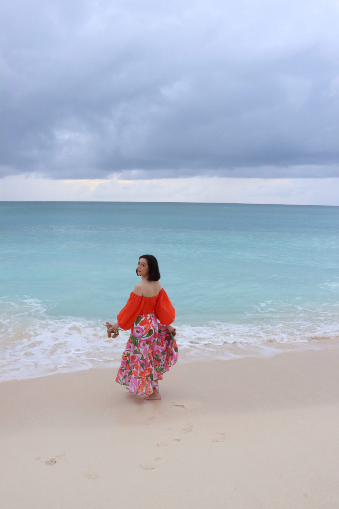 Travel Blogger Jordan Gassner looking over her shoulder while walking along Seven Mile Beach on Grand Cayman Island