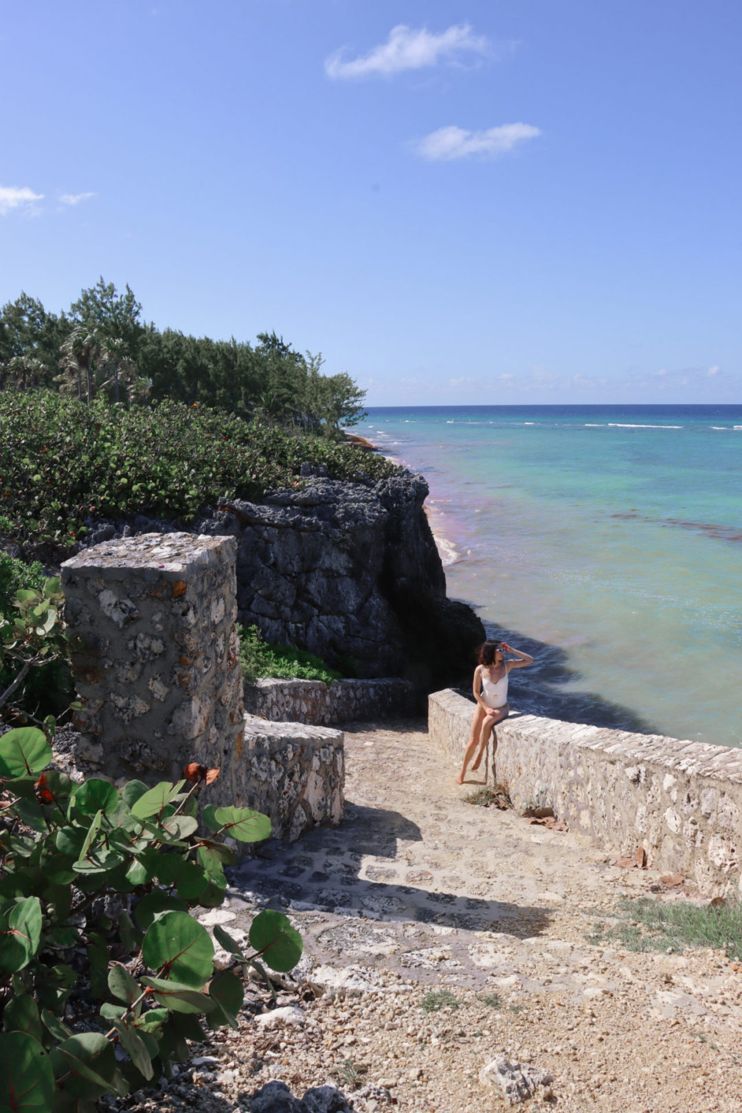 Travel Blogger Jordan Gassner peering out over the ocean from the Barefoot Beach stone staircase on Grand Cayman in the Caribbean