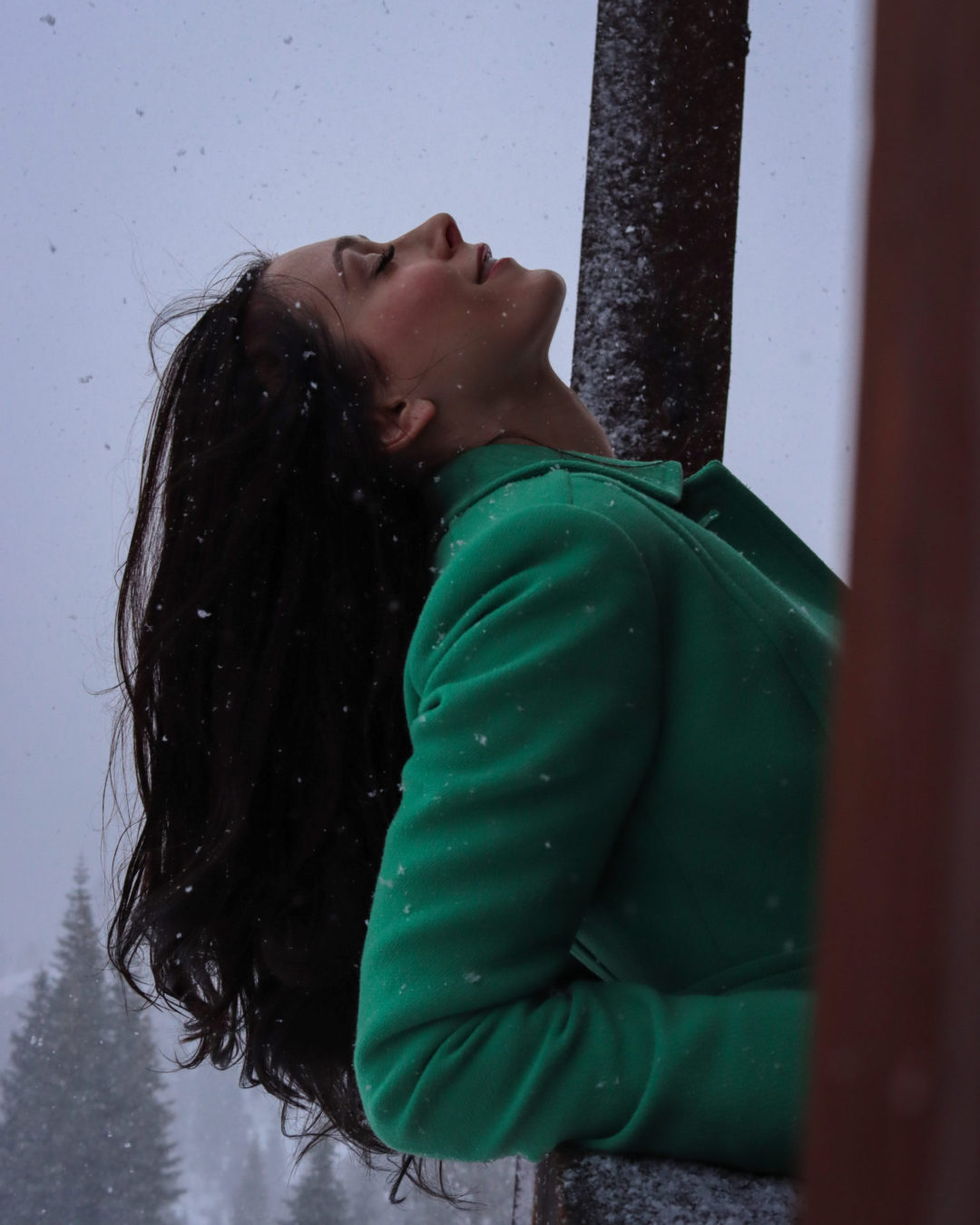 Travel Blogger Jordan Gassner smiling with eyes closed and leaning against a railing of a cabin in Truckee, California