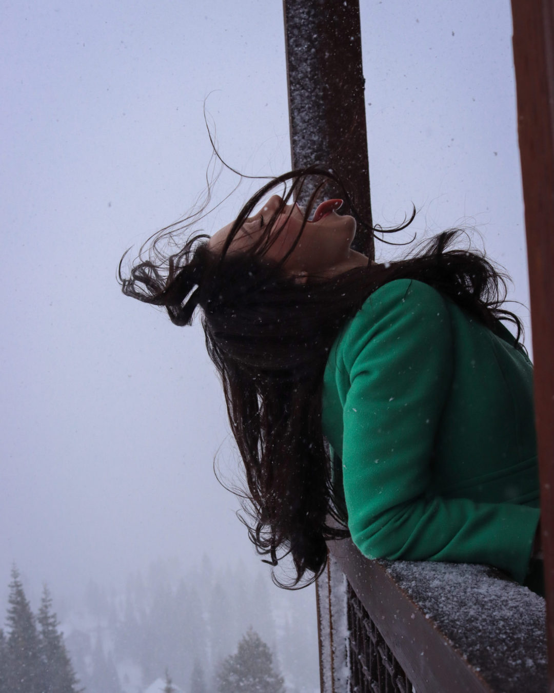 Travel Blogger Jordan Gassner catching snowflakes on her tongue while leaning against a railing of a cabin in Truckee, California