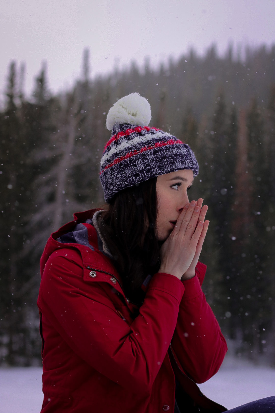 Travel Blogger Jordan Gassner blowing warm air on her hands in Rocky Mountain State Park in Colorado