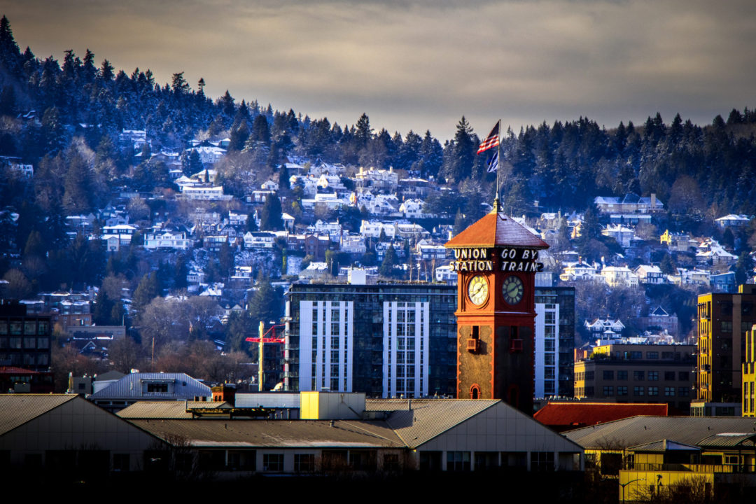 Last Minute US Travel Destinations for the Holidays: Portland, Oregon. An aerial view of Union Station's tower and the snowy mountains