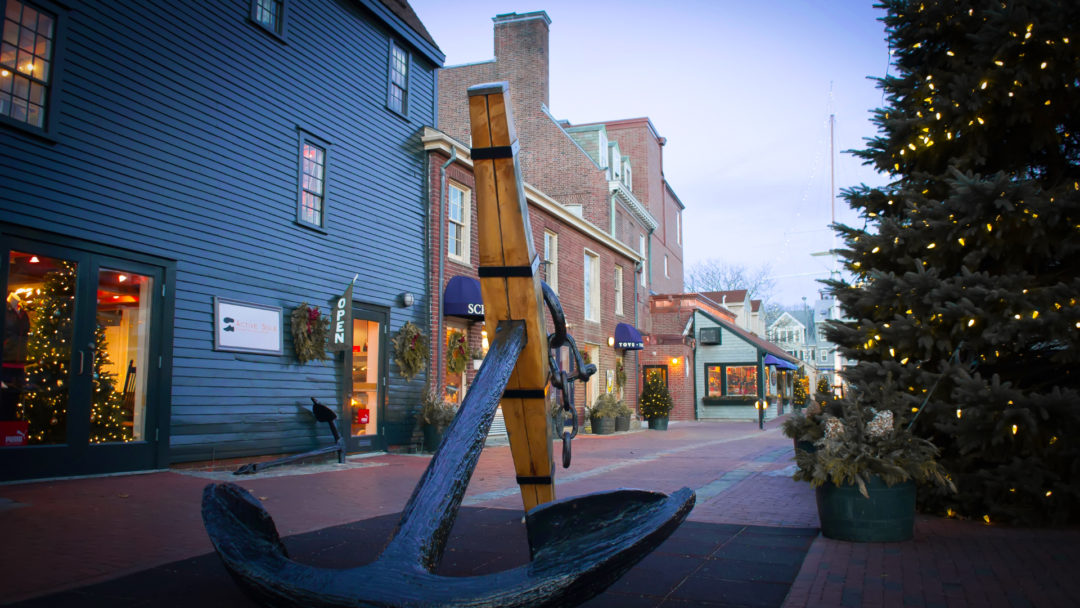 A lit-up Christmas tree near a giant anchor statue in Newport, Rhode Island