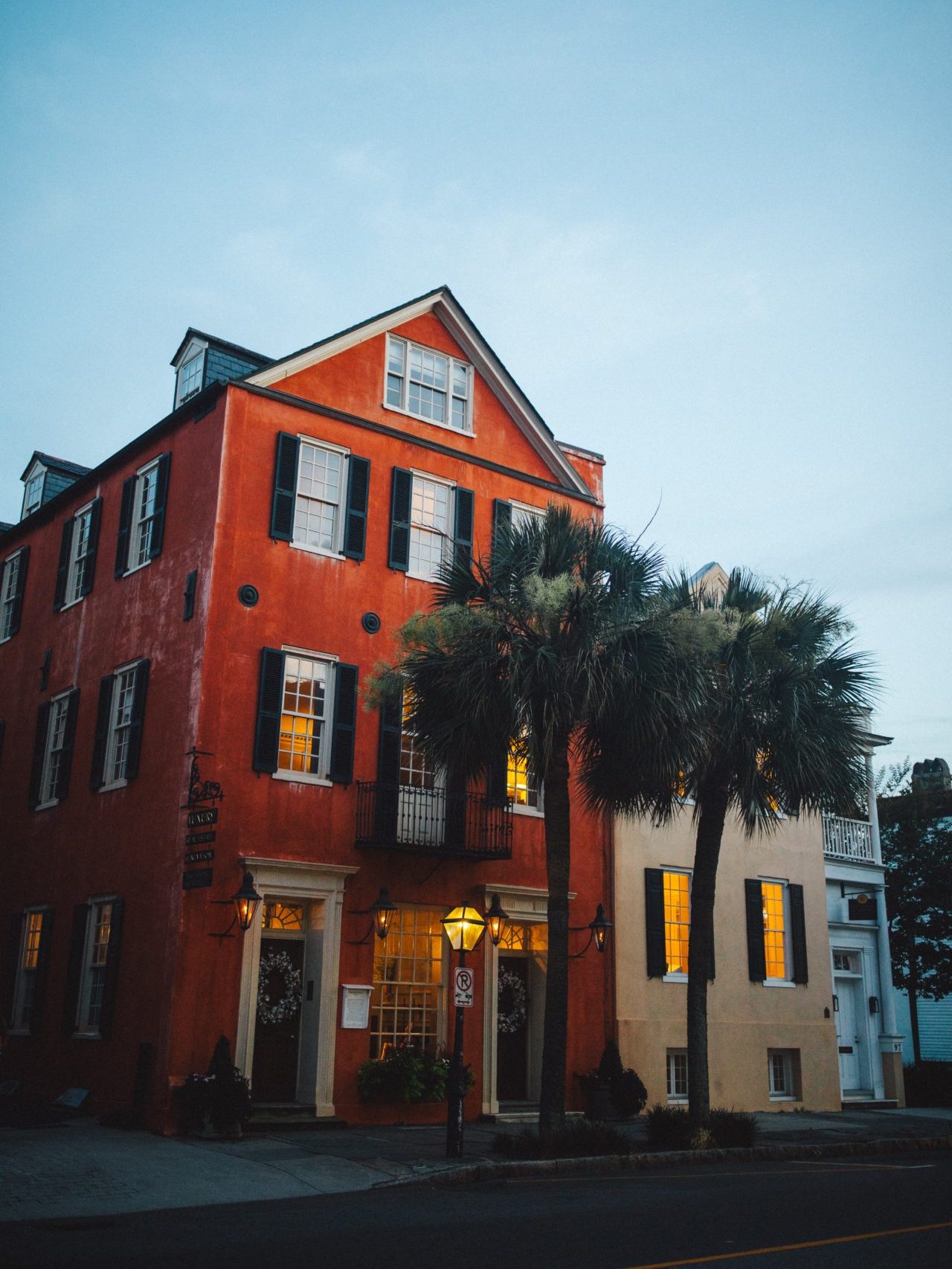 Last Minute US Travel Destinations for the Holidays: Charleston, South Carolina. Historic homes decorated with Christmas wreaths and standing behind two sets of palm trees