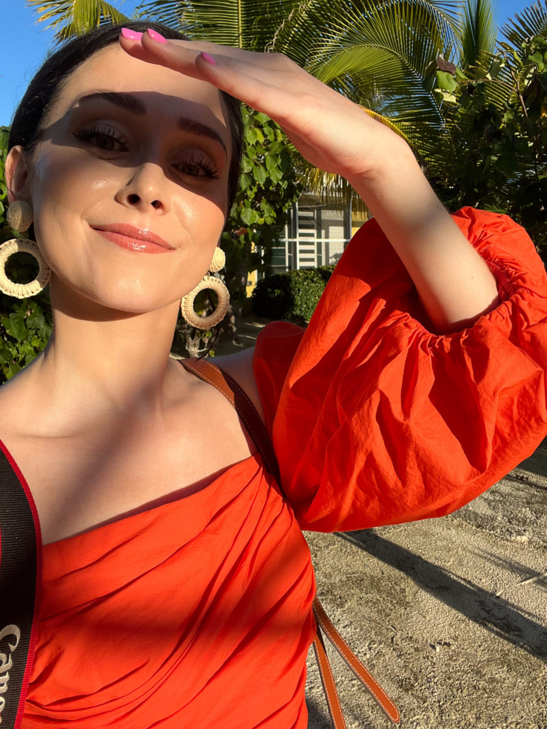 Travel Blogger Jordan Gassner shielding her eyes from the sun and taking a selfie before getting in the car for dinner in Cayman Islands