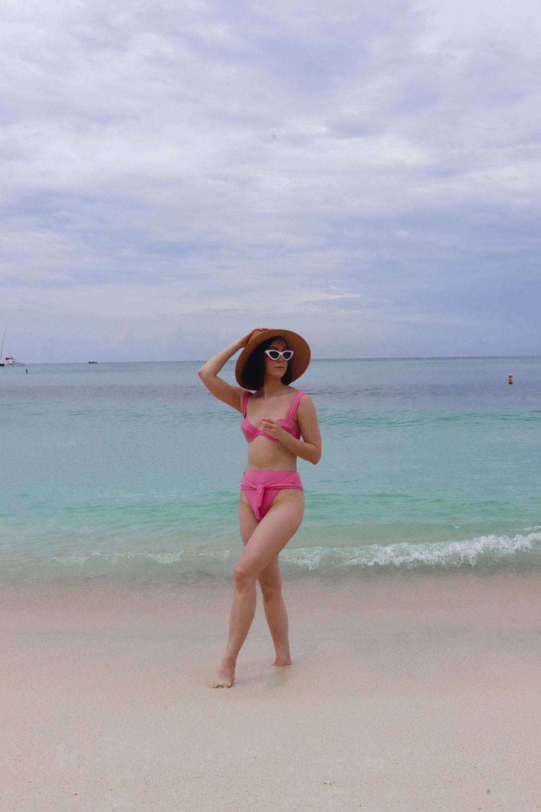 Travel Blogger Jordan Gassner wearing a straw hat and white sunglasses and walking the Governor's Beach shoreline