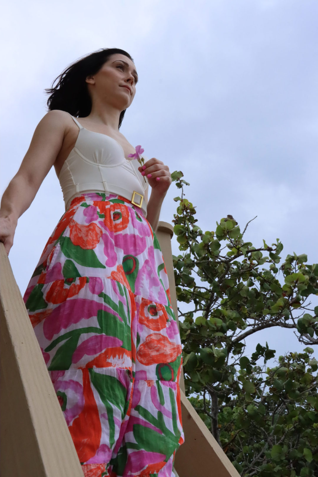 A Low angle photo of Travel Blogger Jordan Gassner holding a flower on a pier on the North Side of Cayman Islands