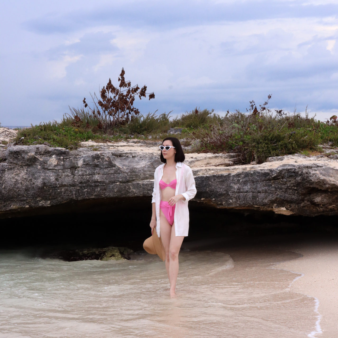 Travel Blogger Jordan Gassner walking along the shore at the rocky Smith Barcadere Beach on Grand Cayman in the Caribbean
