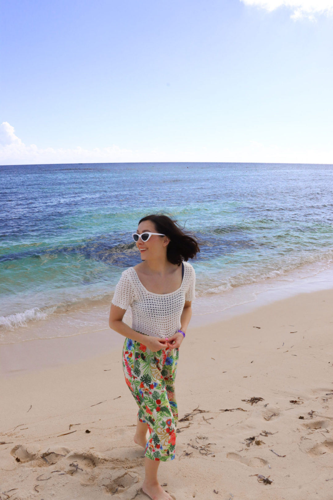Travel Blogger Jordan Gassner smiling and walking away from the water on Spotts Beach in the Cayman Islands