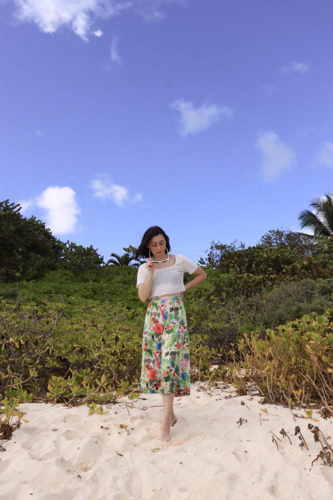 Visiting Cayman Islands: Travel Blogger Jordan Gassner taking off her sunglasses near the plants at the top of Spotts Beach