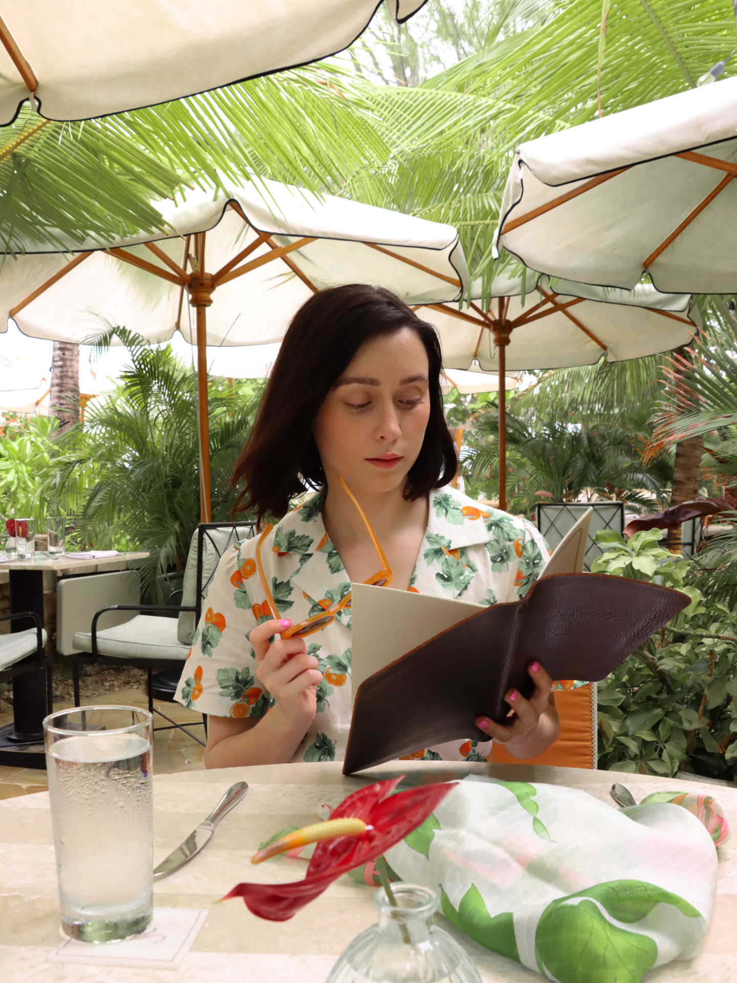 Travel Blogger Jordan Gassner perusing the menu at Tillies Restaurant in Cayman Islands while wearing an oranges dress from WeWoreWhat